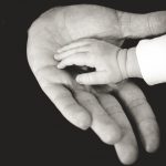 FAQs about counselling and psychotherapy:A large hand reaches for a baby's hand